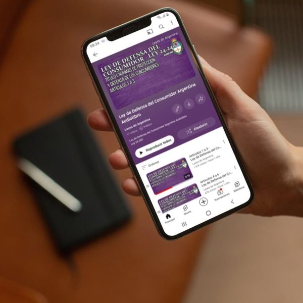 Una mano sostiene un celular que reproduce el audiolibro de la Ley de Defensa del Consumidor