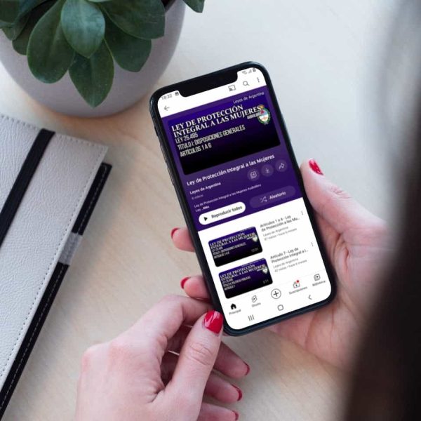 Una mujer sostiene en sus manos un celular que reproduce el audiolibro de la Ley de Protección Integral a las Mujeres.